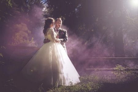 Bride and groom standing in light mist and hazy sunshine - Picture by Simon Emmett Photography