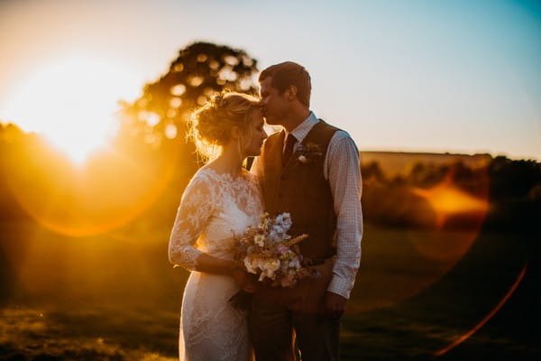 Groom kissing bride on head in hazy sunshine - Picture by Tom Smith Photography