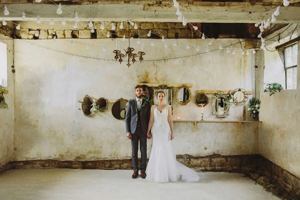 Bride and groom standing us straight in room with mirrors on wall - Picture by Luke Hayden Photography