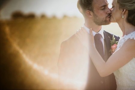 Bride and groom kissing a sun catches camera lens - Picture by Lee Dann Photography