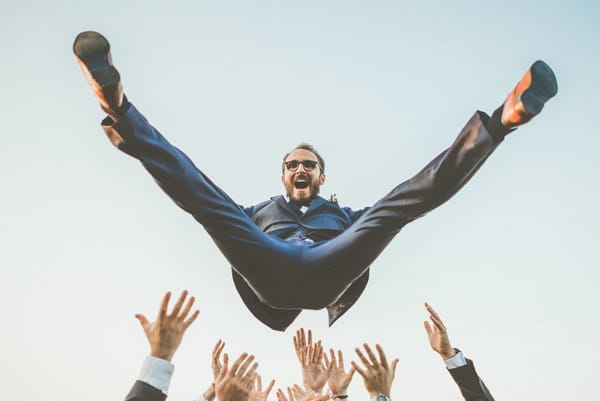 Groom being throw into the air by groomsmen - Picture by David Rochas Photographe