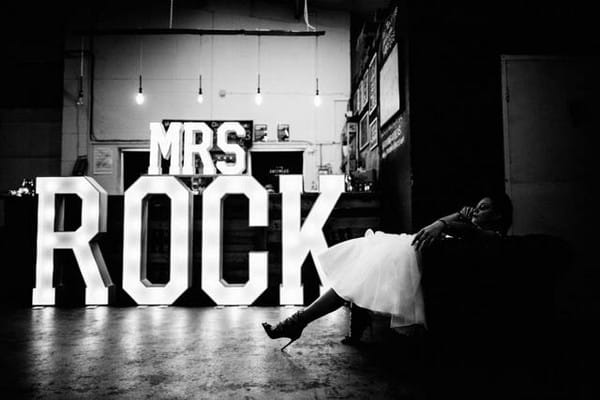 Bride sitting near 'Mrs Rock' illuminated letters - Picture by Vickerstaff Photography