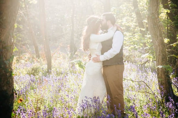 Bride and groom standing amongst flowers in hazy sunshine - Picture by Andrea Kuehnis Photography