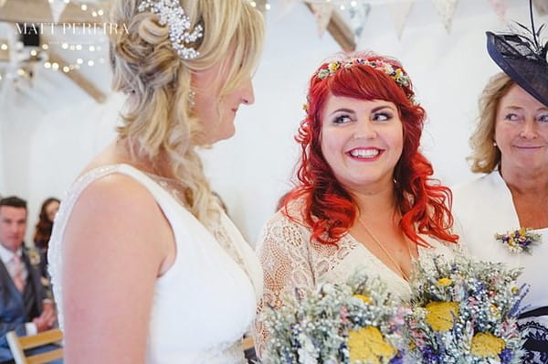 Brides smiling at each other at altar