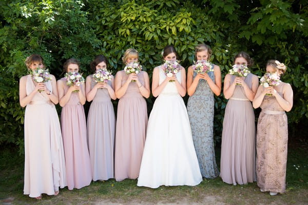 Bridesmaids with bouquets in front of their faces