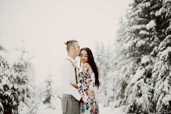 Man kissing fiancée's head in snow