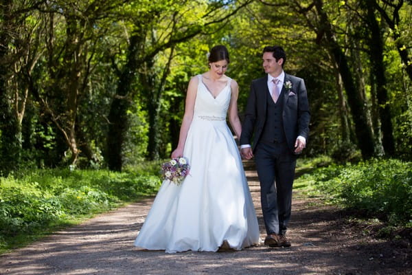 Bride and groom walking holding hands in grounds of Kings Weston House