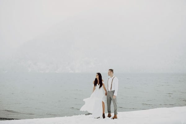 Couple standing next to water in the snow