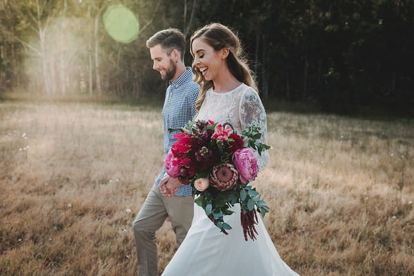 Bride holding bouquet as she walks with groom