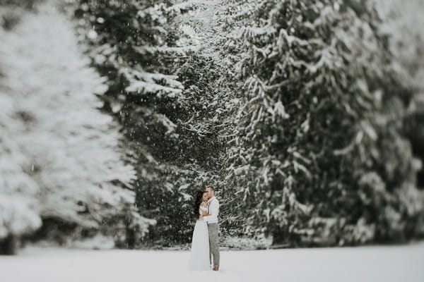 Couple standing in woodland in snow