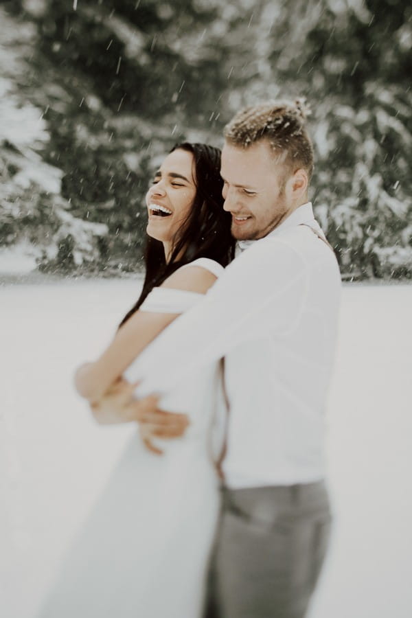 Woman laughing as fiancé holds her from behind
