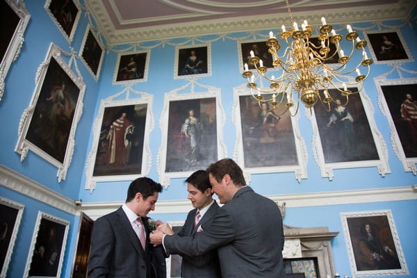 Groomsmen adjusting groom's buttonhole at Kings Weston House