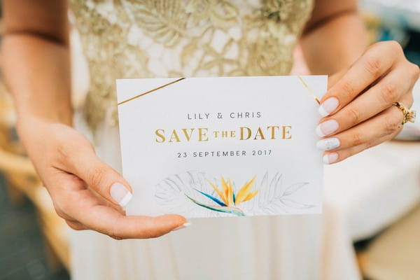 Bride holding tropical styled wedding save the date