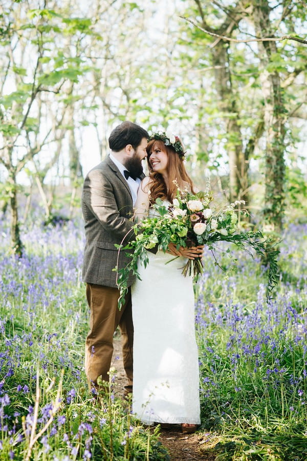 Couple standing in bluebells in woodland