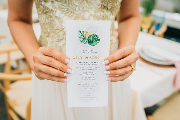 Bride holding tropical styled wedding order of the day