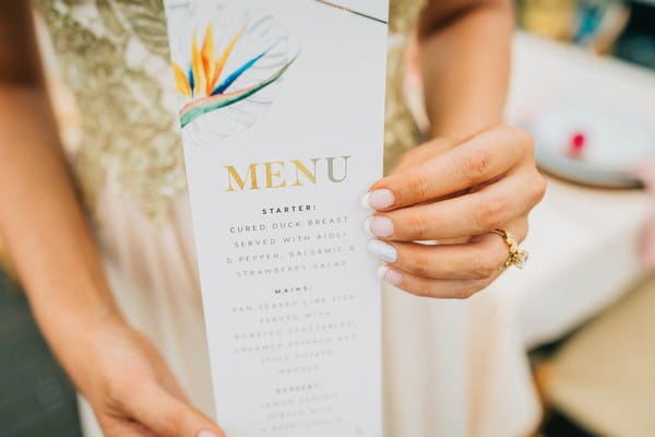 Bride holding tropical styled wedding menu