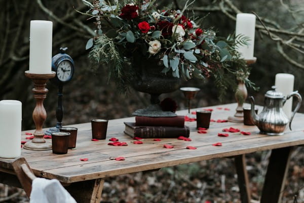 Books, votives, rose petals and candles on wooden table