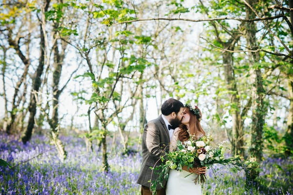 Couple kissing in bluebells in woodland