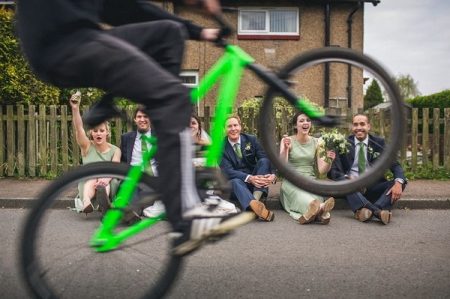 Bridal party sitting watching someone pull a wheelie on a bicycle - Picture by Andy Hudson Photography