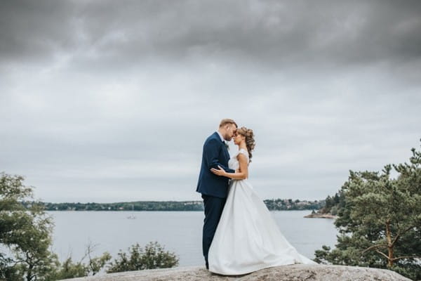 Bride and groom touching heads on rock in front of the sea - Picture by Anette Bruzan Photography