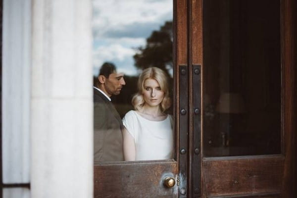 Bride and groom standing at window of door - Picture by Kitty Wheeler Shaw Photography