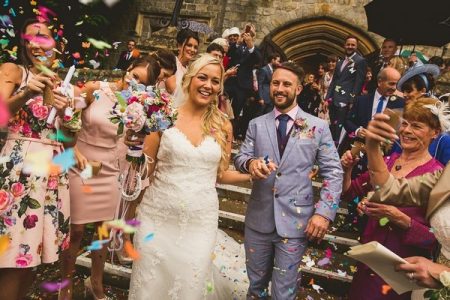 Bride and groom holding hands as guests throw confetti - Picture by The Springles