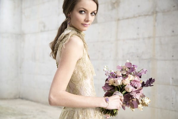 Bride in gold wedding dress holding purple bouquet