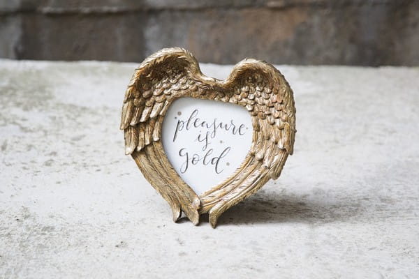 Pleasure is gold sign in gold feather heart frame