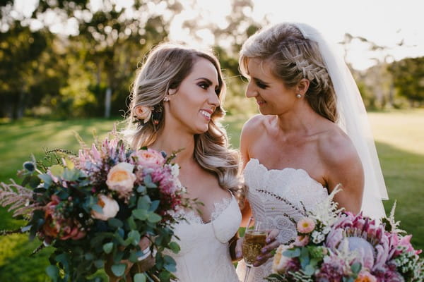 Two brides smiling at each other