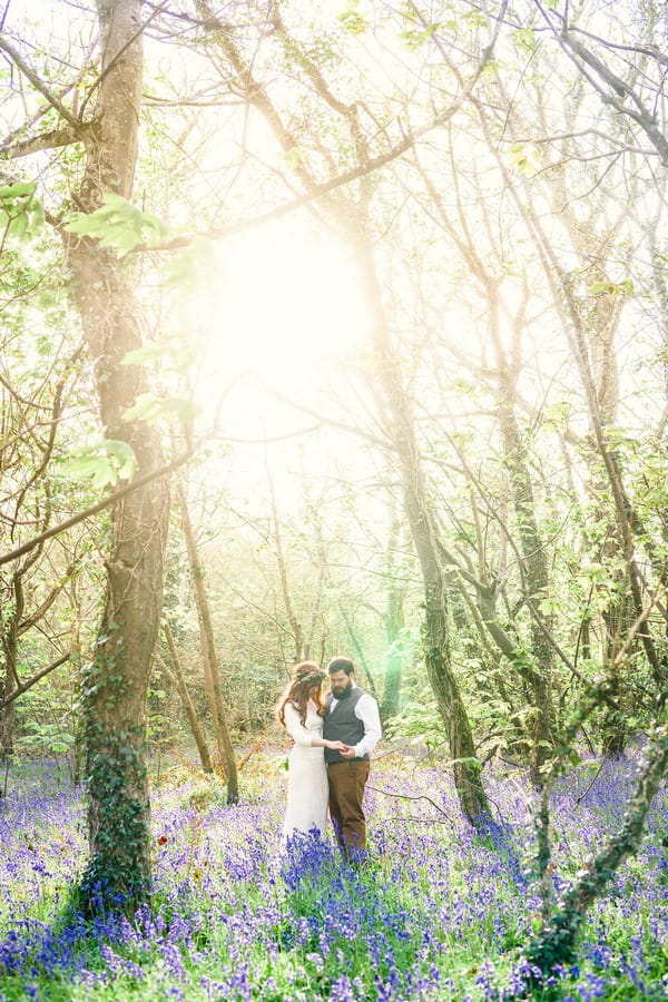 Bride and groom in woodland in hazy sunshine