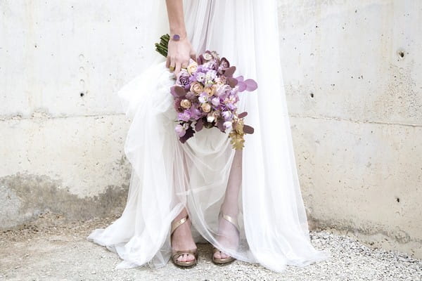 Bride's purple bouquet and gold shoes