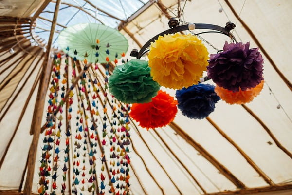 Colourful pom poms hanging in wedding marquee