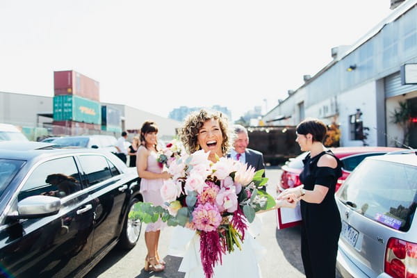 Happy bride carrying large bouquet