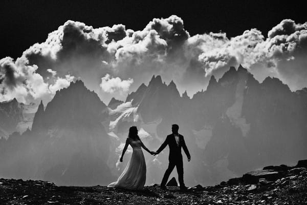 Bride and groom with mountains and clouds in background - Picture by Franck Boutonnet Photography