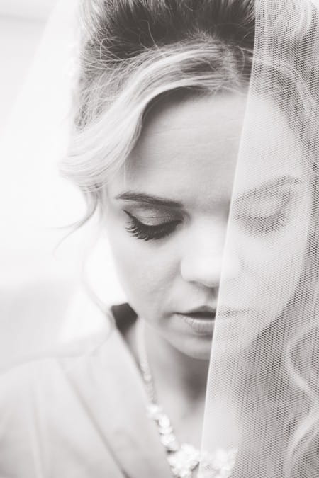 Black and white picture of bride with veil over half her face - Picture by LJWrightphotography