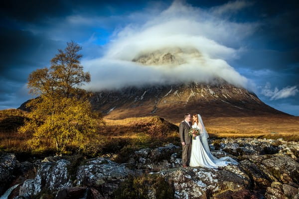 Bride and groom in front of Glencoe hill surrounded by clouds - Picture by Stuart Craig Photography