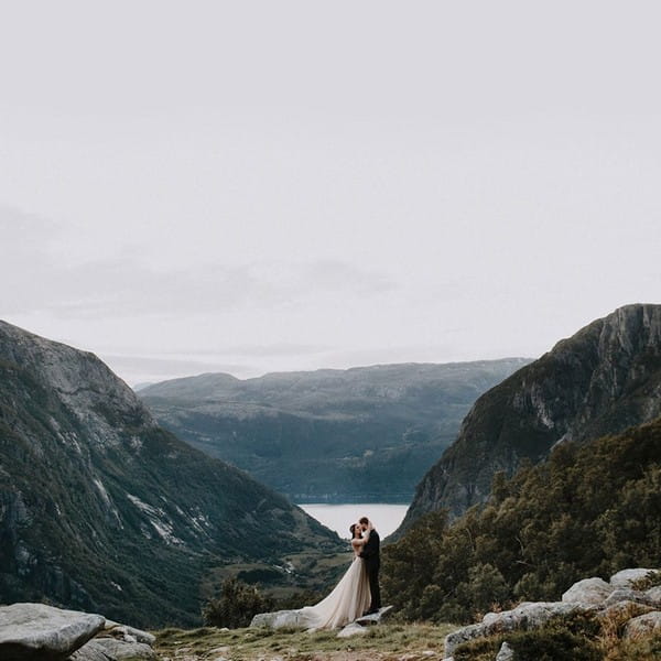 Bride and groom kissing with mountains in the background - Picture by Iskra Photography