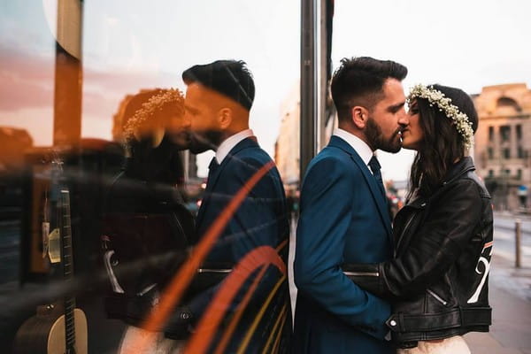 Bride and groom kissing against window showing their reflection - Picture by Fiona Higgins Photography