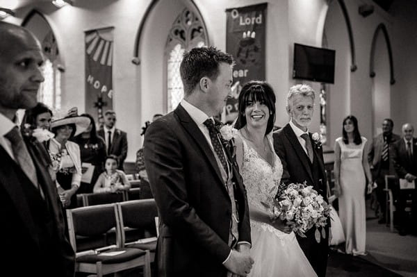 Bride and groom smiling at each other at the altar