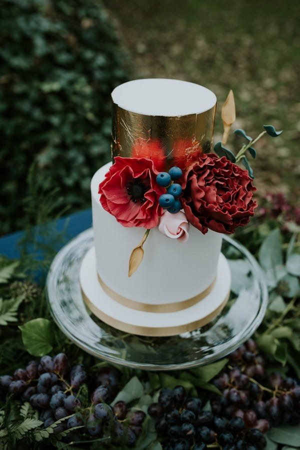 White and gold wedding cake with red flowers