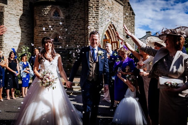 Wedding guests throwing confetti over bride and groom