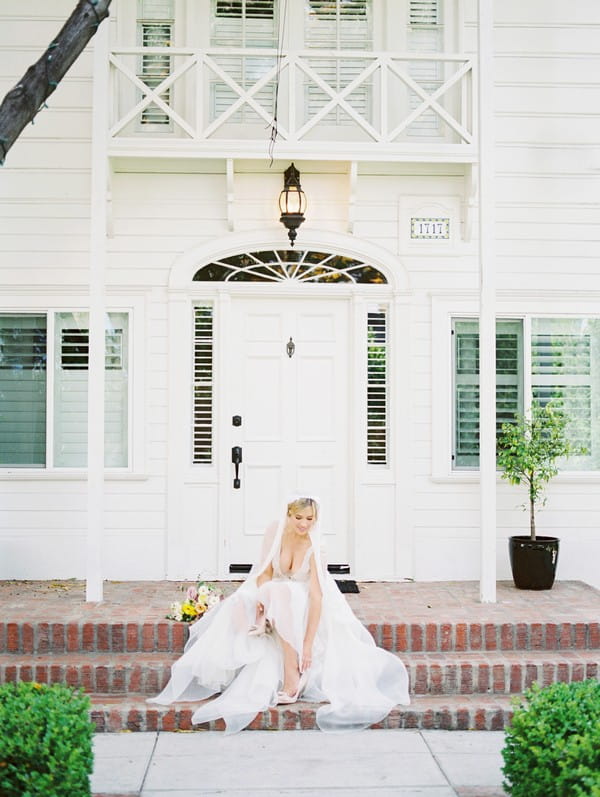 Bride sitting on steps of Lombardi House