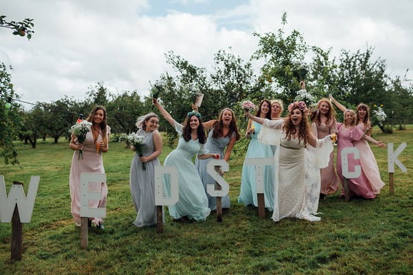 Bride and bridesmaids posing by Wedstock sign