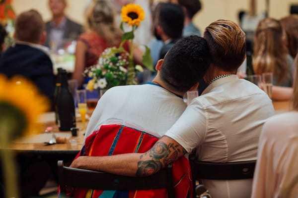 Guests with arms around each other as they listen to wedding speeches