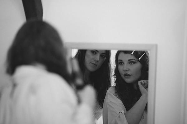 Bride and bridesmaid looking in mirror getting ready