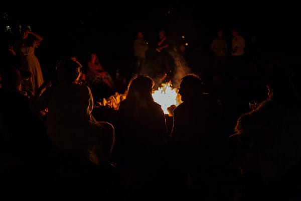 Wedding guests sitting around campfire