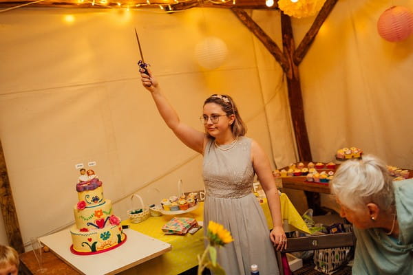 Lady holding knife in the air for cake cutting