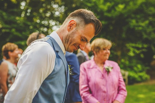 Groom looking down as he waits for bride