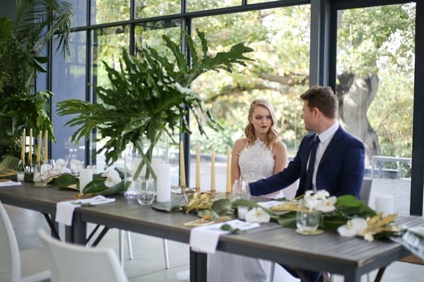 Bride and groom sitting at wedding table with botanical styling