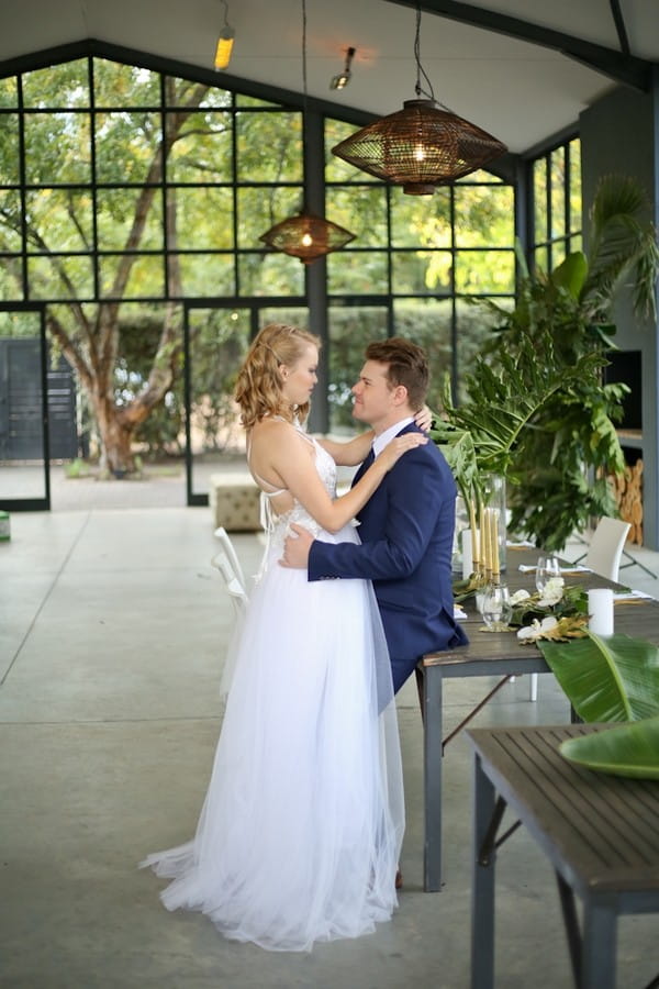 Groom sitting on edge of table facing bride